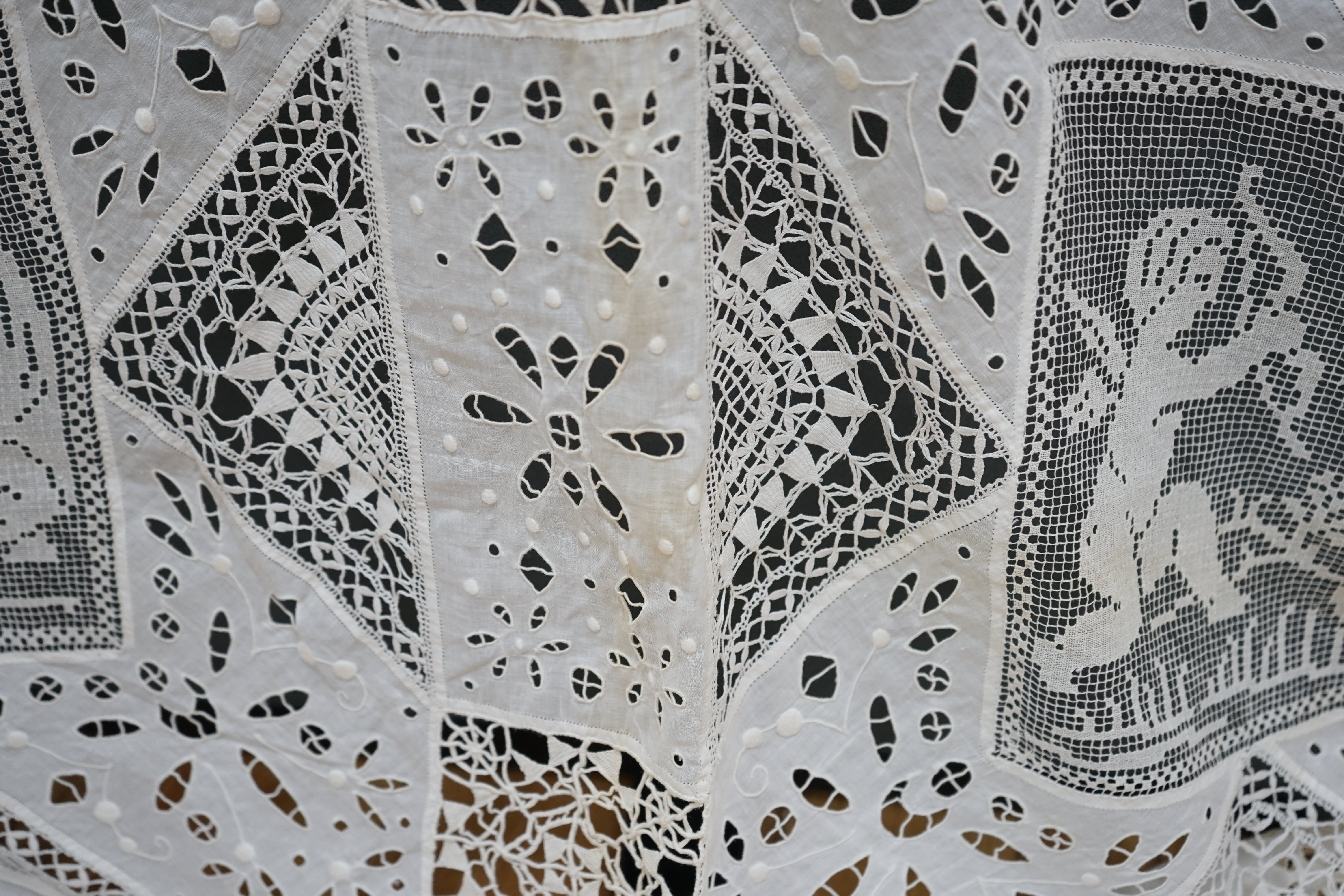 An early 20th century Italian bedcover, worked with fillet lace insertions of putti, white multi patterned fine linen cut work squares and similar multi patterned hand needle lace insertions, creating a unique and totall